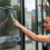 Professional cleaner using a squeegee on storefront glass, showcasing effective cleaning techniques for urban businesses